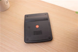 Black rectangular device with a red light on a wooden surface